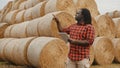 Young african man,working on tablet in front of the hay roll stack. Smart farming concept