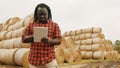 Young african man,working on tablet in front of the hay roll stack. Smart farming concept