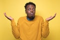 Young african man in yellow clothes shrugging shoulders Royalty Free Stock Photo