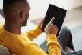 Young african man in yellow sweatshirt using table for working and education, touching tablet screen. Internet support Royalty Free Stock Photo