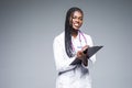 Young african medical intern doctor writing prescription on clipboard isolated on gray background Royalty Free Stock Photo