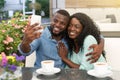 Young african man taking a photo with his mobile phone in cafe