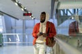 Young African millennial man traveler using mobile phone while waiting for flight in airport Royalty Free Stock Photo