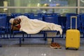 Young African passenger man sleeping under plaid waiting for flight feel cold. Long night connection Royalty Free Stock Photo