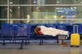 Young African passenger man sleeping under plaid waiting for flight feel cold. Long night connection Royalty Free Stock Photo