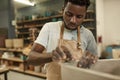 African ceramist sanding a clay pot at a studio workbench Royalty Free Stock Photo