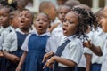 Young African school girl with beautifully decorated hair singing and dancing at pre-school in Matadi, Congo, Africa