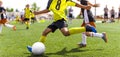 Young african soccer player running fast and kicking white football ball. Youth footballers compete in tournament match. Soccer Royalty Free Stock Photo