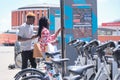 Young african tourists renting a bike at a bicycle rental service machine