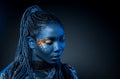Young African woman with afro hairstyle and golden shiny makeup. Studio shot. Blue 2020 trend color