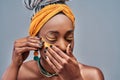 Young african woman with bare shoulders standing isolated on grey background putting on golden under eye patches Royalty Free Stock Photo