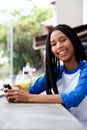 Young african woman with cell phone sitting at cafe Royalty Free Stock Photo