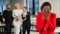 Young african woman crying because of the ridicule of colleagues. Racial discrimination in the office.