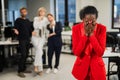 Young african woman crying because of the ridicule of colleagues. Racial discrimination in the office.