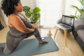 Young African woman doing pilates virtual fitness class with laptop at home Royalty Free Stock Photo