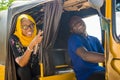 young african woman giving directions to the driver of an auto rickshaw taxi, pointing in the direction she wants to go Royalty Free Stock Photo