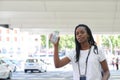 Young african woman hailing a taxi and holding a refreshing drink