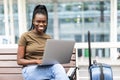 Young african woman with hand luggage in international airport terminal, working on her laptop while waiting for flight Royalty Free Stock Photo