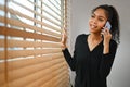 Young African woman having phone conversation and looking through a window Royalty Free Stock Photo