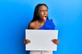 Young african woman holding blank empty banner angry and mad screaming frustrated and furious, shouting with anger