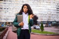 Young african woman holding laptop pointed side standing outdoors on street