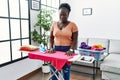 Young african woman ironing clothes at home skeptic and nervous, frowning upset because of problem