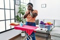 Young african woman ironing clothes at home sleeping tired dreaming and posing with hands together while smiling with closed eyes Royalty Free Stock Photo