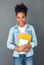 Young african woman isolated on grey wall studio casual daily lifestyle holding notebooks Royalty Free Stock Photo