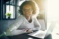 Young African woman laughing while working on a laptop