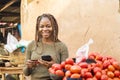 young african woman in a local african market using her mobile phone and credit card Royalty Free Stock Photo