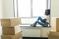 Young african woman moving in house sitting on the windowsill. Relocation concept Royalty Free Stock Photo