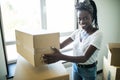 Young african woman moving into new apartment holding cardboard boxes with belongings Royalty Free Stock Photo
