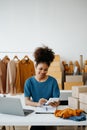 Young African woman running online store Startup small business SME, using smartphone or tablet taking receive and checking online Royalty Free Stock Photo