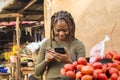 young african woman selling in a local african market using her mobile phone and credit card Royalty Free Stock Photo