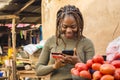 young african woman selling in a local african market using her mobile phone and credit card to do a transaction online Royalty Free Stock Photo