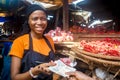 Young african woman selling food stuff in a local african market collecting money from a paying customer