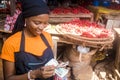 Young african woman selling in a local african market counting money and smiling Royalty Free Stock Photo