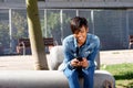 Young african woman sitting outside and using mobile phone Royalty Free Stock Photo