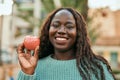 Young african woman smiling happy holding fresh red apple at the city Royalty Free Stock Photo