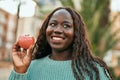 Young african woman smiling happy holding fresh red apple at the city Royalty Free Stock Photo