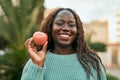 Young african woman smiling happy holding fresh red apple at the city Royalty Free Stock Photo