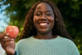 Young african woman smiling happy holding fresh red apple at the park Royalty Free Stock Photo