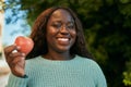 Young african woman smiling happy holding fresh red apple at the park Royalty Free Stock Photo