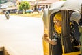 young african woman smiling while using her mobile phone, sitting in the back seat of an auto rickshaw taxi Royalty Free Stock Photo