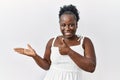 Young african woman standing over white isolated background showing palm hand and doing ok gesture with thumbs up, smiling happy Royalty Free Stock Photo