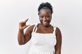 Young african woman standing over white isolated background smiling and confident gesturing with hand doing small size sign with Royalty Free Stock Photo