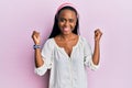 Young african woman wearing casual clothes over pink background screaming proud, celebrating victory and success very excited with Royalty Free Stock Photo