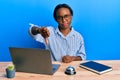 Young african woman working at hotel reception using laptop looking unhappy and angry showing rejection and negative with thumbs