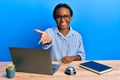 Young african woman working at hotel reception using laptop smiling friendly offering handshake as greeting and welcoming Royalty Free Stock Photo