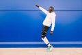 Young afro American black man dancing near a blue wall while raise his fist while listening music
